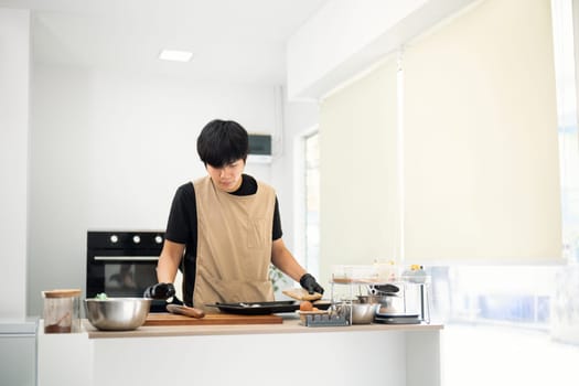 Handsome young asian man arranging cookie dough on a baking tray.