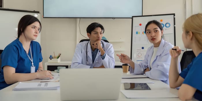 A diverse team of healthcare professionals, including a physician and nurses, discuss strategies for improving patient care during a meeting.
