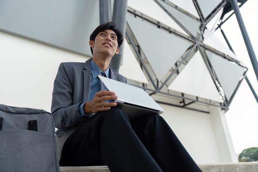 A young man in a suit thoughtfully considers financial strategies while working outdoors, merging nature with business.