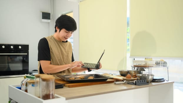 Small business owner in an apron taking online orders on his digital tablet.