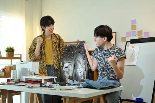 Young fashion designers celebrating a successful creation at their workplace.