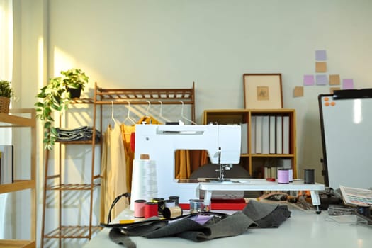 Fashion design studio with sewing tools, colorful thread spools and fabric swatches.