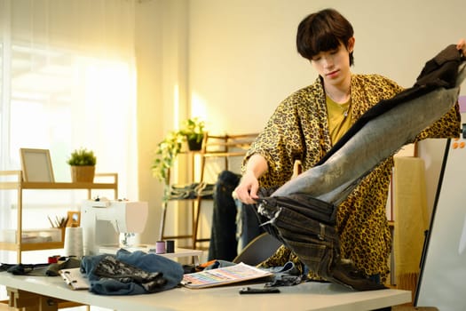 Young stylish designer examining a pair of jeans in a creative studio..
