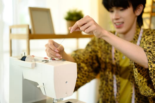 Cropped shot of young fashion designer threading a sewing machine.