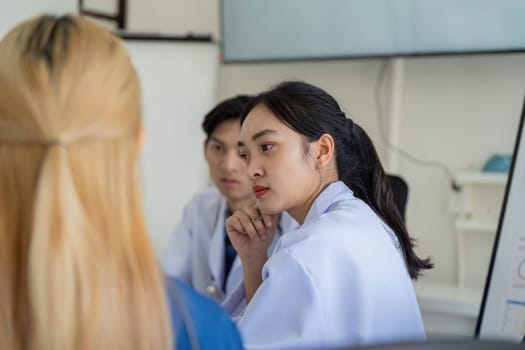 A group of healthcare professionals, including a doctor and nurse, engage in a thoughtful discussion, analyzing data and strategies.