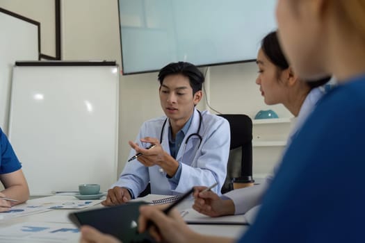 A diverse team of healthcare professionals, including a physician and nurses, collaborate in a meeting focused on patient analysis and strategies.
