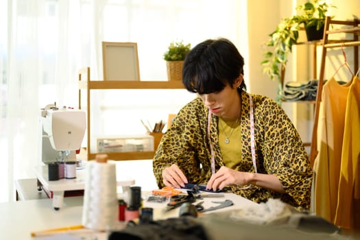 Young fashion designer working on a clothing project in stylish studio.