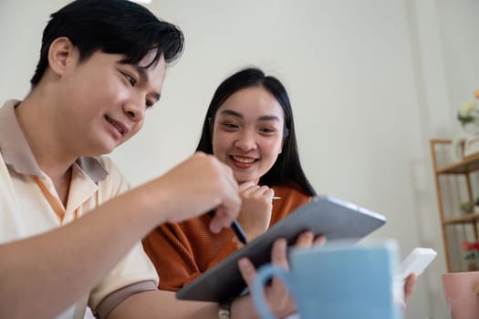 A young couple engages in financial discussions, using a tablet to manage their income and bills effectively.