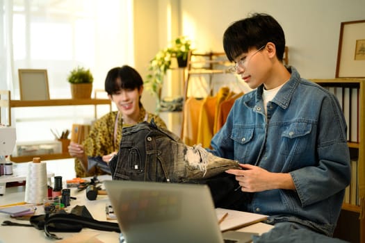 Two fashion designers collaborating on custom denim project in a stylish studio.