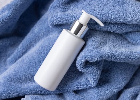 White blank one pump bottle on blue towel in bathroom closeuptop view, brand packaging mockup. Natural handmade cosmetic product - cream, lotion or soap for daily face or handcare, copy space