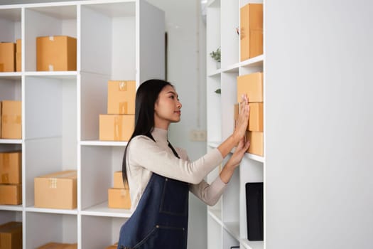 A young woman organizes boxes in a modern office space, reflecting her entrepreneurial spirit and commitment to her business.