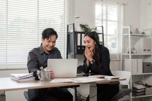 Two colleagues share a joyful moment in an office, celebrating success and teamwork with smiles and laughter.