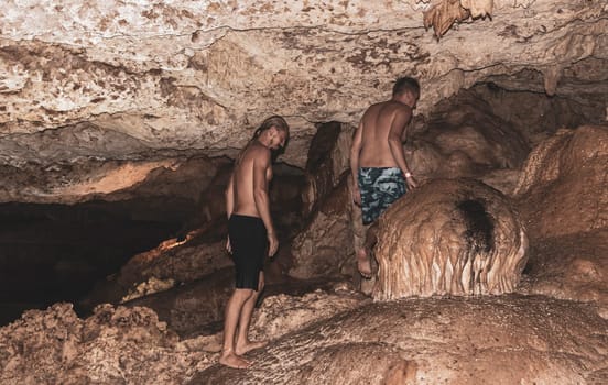 Mean male tourists friendsare posing and climbing in the turquoise green blue water and rocks in cenote Yaxmulito in Tulum Quintana Roo Mexico.