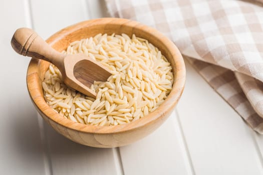 Orzo, kritharaki, risoni pasta. Uncooked dry pasta in bowl on a white table.