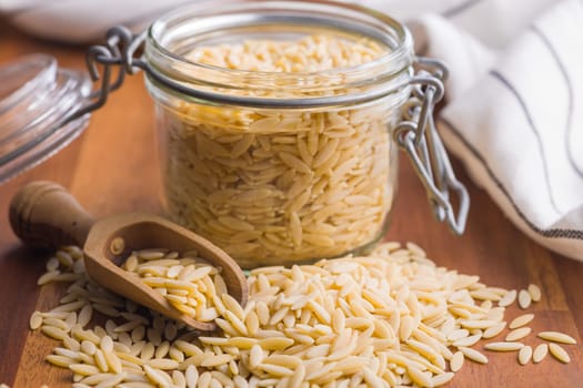 Orzo, kritharaki, risoni pasta. Uncooked dry pasta on a wooden table.