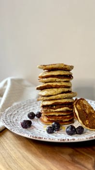 stack of banana pancakes with honey and berries on a light plate
