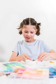 Little girl enjoys crafting colorful bracelets with vibrant clay beads set.