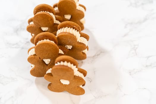 Gingerbread cookies filled with eggnog buttercream stand out, their rich hue complementing the eggnog buttercream, against a gentle background. These festive treats exude a homemade allure.