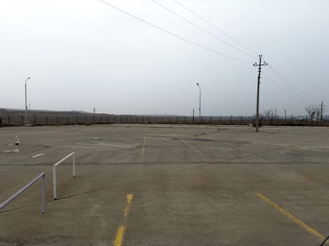 Empty street parking for cars with concrete pavement and markings for parking spaces. Large area for cars without anyone. Country parking for car exhibition, area for parking and displaying cars