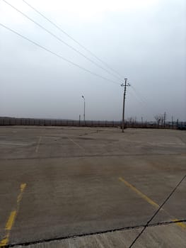 Vertical photograph of old abandoned car parking lot. Empty parking lot for cars with markings for parking spaces on street. Large parking lot with concrete surface for cars is empty