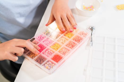 Little girl enjoys crafting colorful bracelets with vibrant clay beads set.