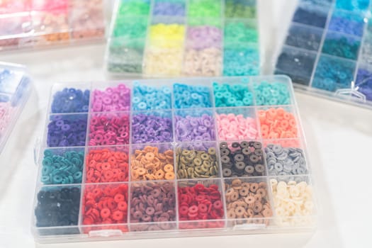 Assorted clay bead boxes neatly arranged on a white table, awaiting a creative kids' craft project.