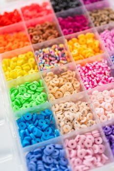 Assorted clay bead boxes neatly arranged on a white table, awaiting a creative kids' craft project.