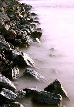 Shore fortification lapped by waves. Long exposure with neutral density filter