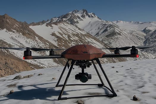 A drone stands on a snow-covered mountain, equipped with a camera, preparing to film the breathtaking scenery of the surrounding peaks.