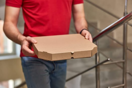 delivery man in red t-shirt holding pizza box on the stairs