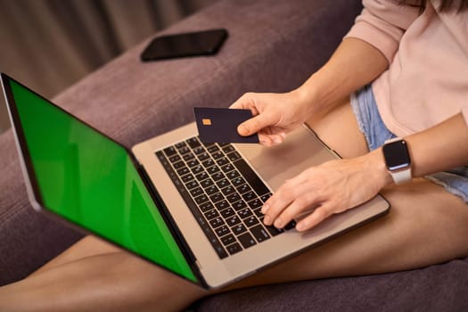 woman using laptop holding credit card, online shopping , close-up