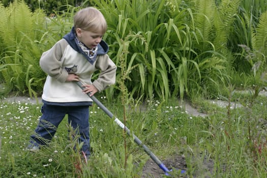 Boy playing in the garden with a shovel