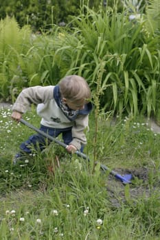 Boy playing in the garden with a shovel