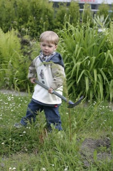 Boy playing in the garden with a shovel