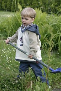 Boy playing in the garden with a shovel