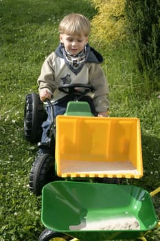 Boy shovels sand into wheelbarrow with excavator