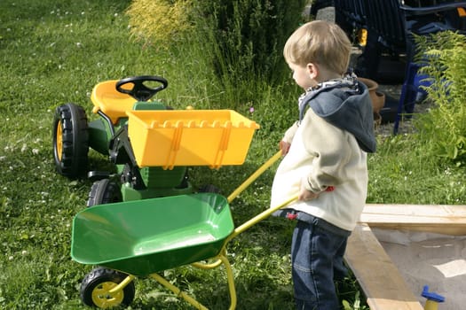Boy driving the wheelbarrow through the garden