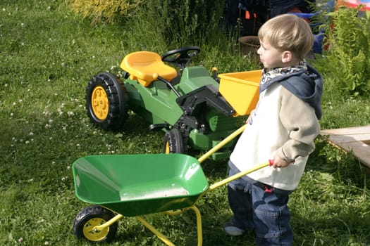 Boy driving the wheelbarrow through the garden