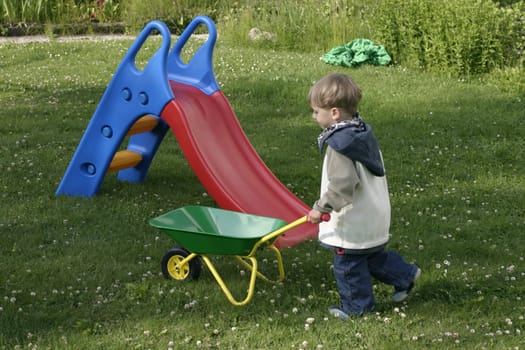 Boy driving the wheelbarrow through the garden