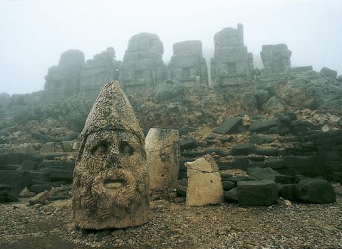 The artificially raised "burial mound"" of Anthiochos I on the 3000m high  Nemrut Dag in Eastern Anatolia,has a diameter of 150m and an altitude of 50m. The five cult figures,originally up to 9m high,embody Greek UN"