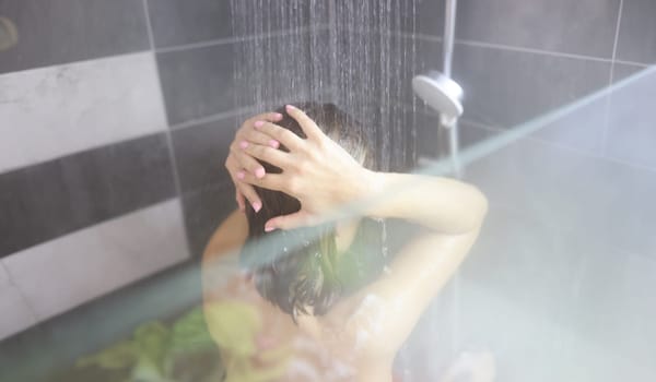 Woman takes hot shower in bathroom. Power and benefits of contrast shower concept