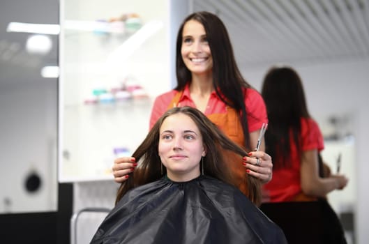 Master hairdresser holds hair of client in beauty salon. Womens hairstyles and styling training courses concept