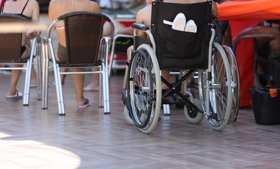 On territory of hotel there is wheelchair in which child sits. Accessible infrastructure for people with disabilities concept