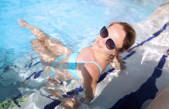 Woman in sunglasses is resting in pool. Water park services concept