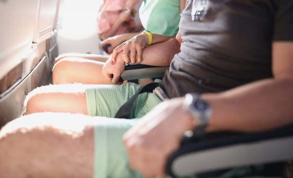 Women's and men's hands firmly hold the armrests in aircraft cabin. How to overcome aerophobia concept