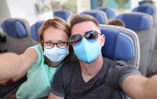 Man and woman wearing medical protective masks on plane. Safe travel to coronavirus pandemic concept