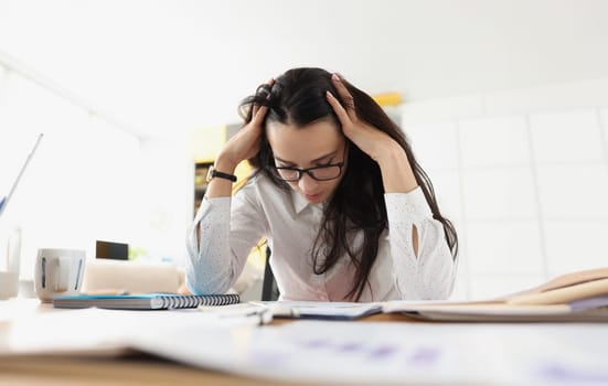 Tired woman bowed her head over her desk with documents. Stressful situations at work concept