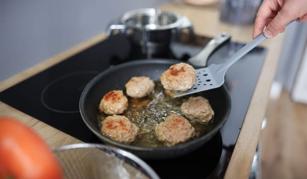 Turn cutlets in frying pan with spatula. How to properly fry cutlets concept