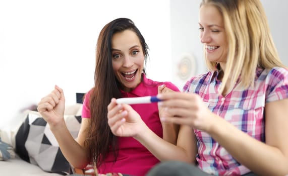 Two joyful women are looking at pregnancy test. First emotions of the expectant mother concept