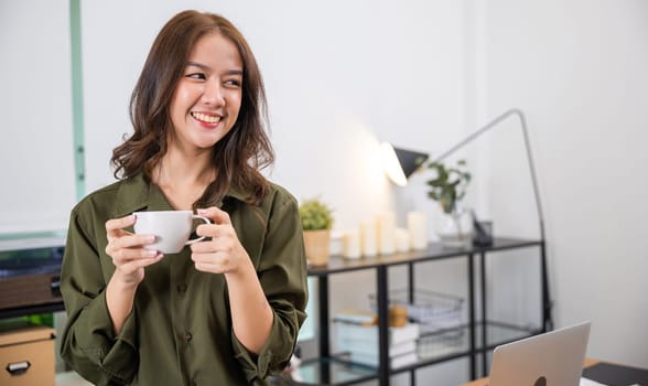 Portrait of Asian young woman holding hot coffee or tea cup in morning while posing, white porcelain mug mock up, Happy beautiful woman relaxing in summer after wakeup at home, lifestyle